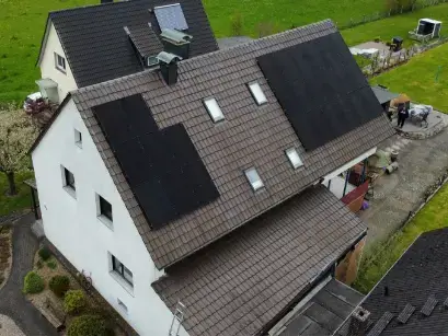 Einfamilienhaus mit Solarmodulen auf dem Dach in ländlicher Umgebung, nachhaltige Energiequelle.