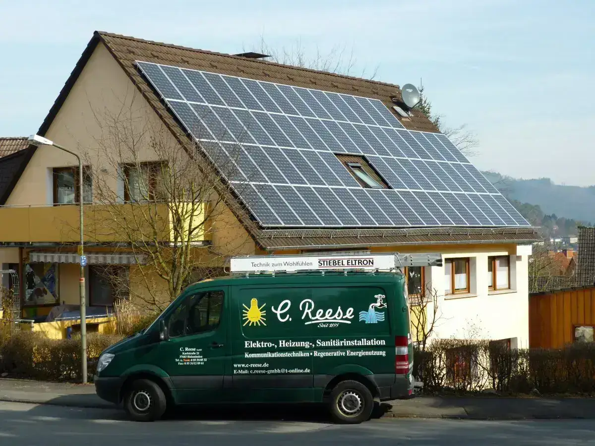 Wohnhaus mit Solaranlage auf dem Dach, Firmenfahrzeug C. Reese für Elektro- und Sanitärdienstleistungen davor.
