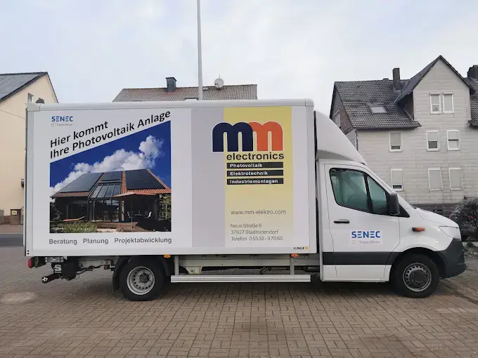 Lieferwagen von MM Electronics mit Werbung für Photovoltaikanlagen in einer Wohngegend.
