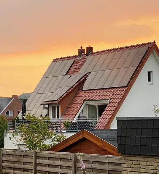 Modernes Haus mit Solarpanelen auf dem Dach bei Sonnenuntergang, nachhaltige Energie in einer Wohngegend.