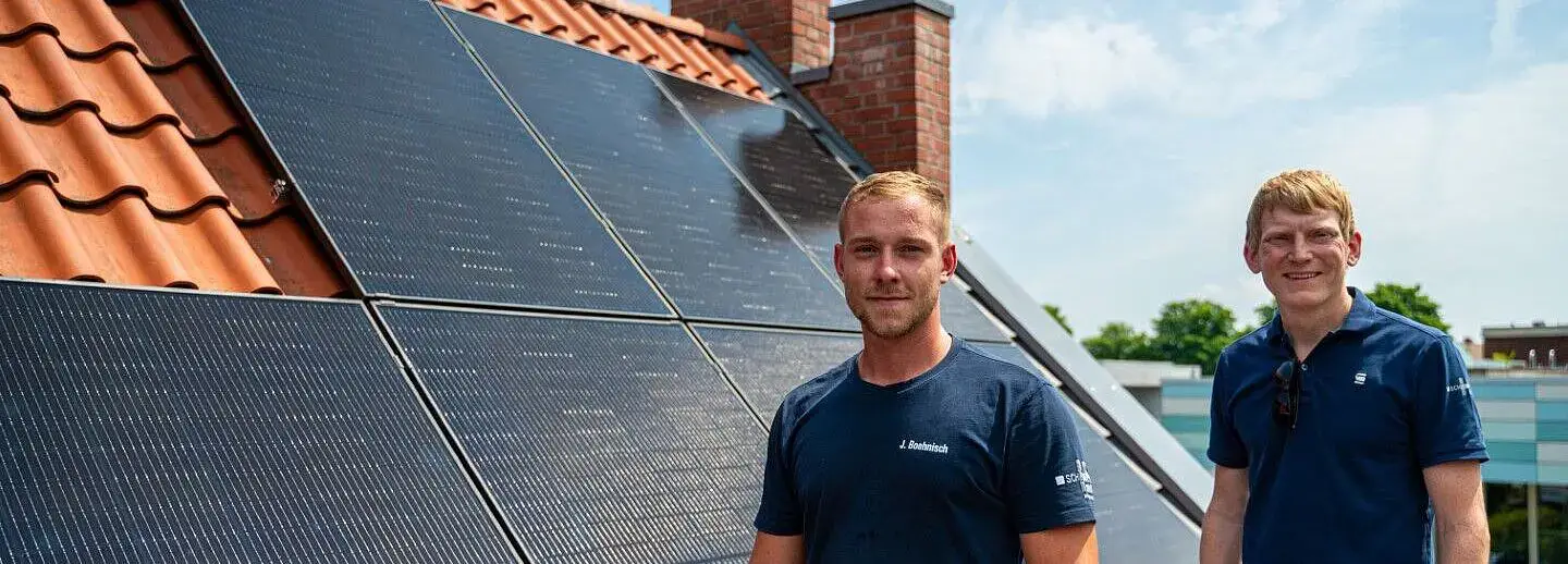 Zwei männer auf einem Dach stehen vor einer Photovoltaik-Anlage