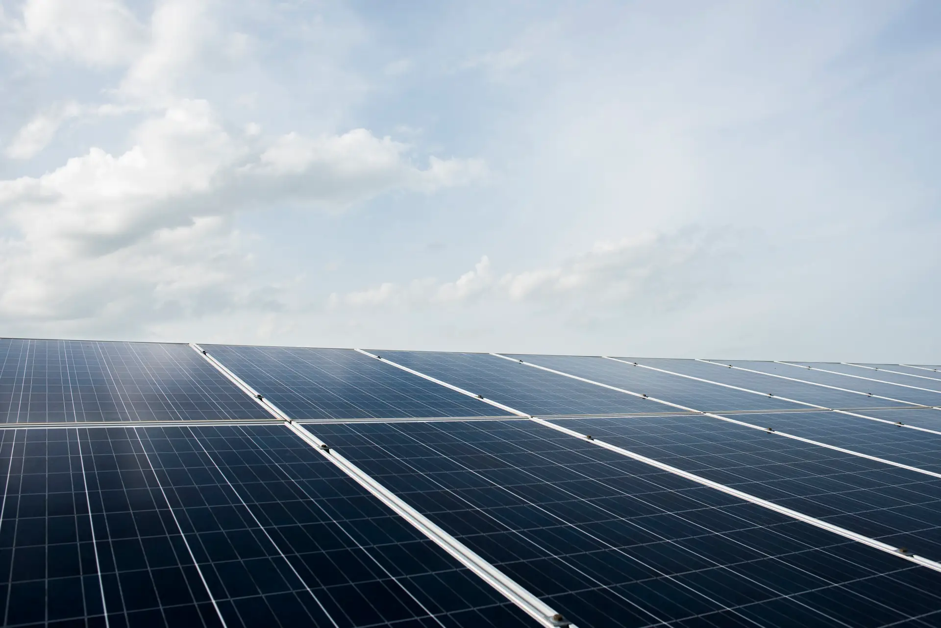 Solarmodule auf einem Dach unter einem bewölkten Himmel, die erneuerbare Energie erzeugen.