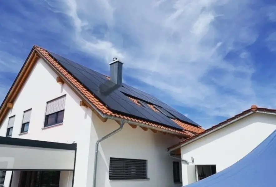 Ziegeldach eines Hauses mit installierten Solarpanelen unter blauem Himmel. Umweltfreundliche Energiequelle.