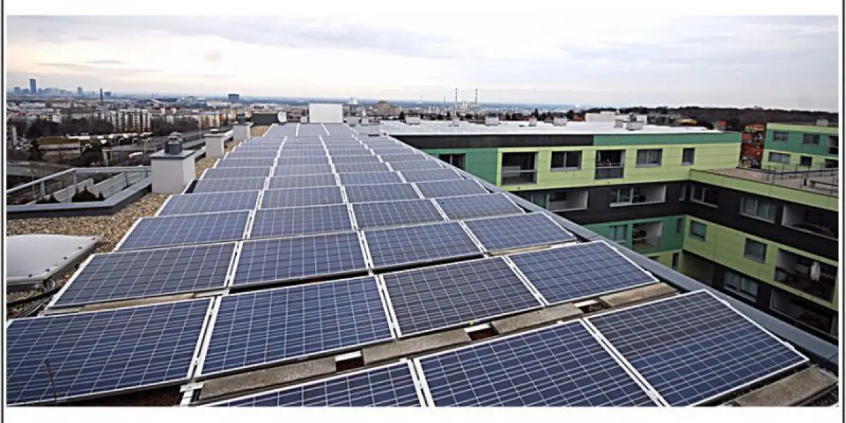 Solaranlagen auf dem Dach eines modernen Gebäudes in einer städtischen Umgebung bei bewölktem Himmel.