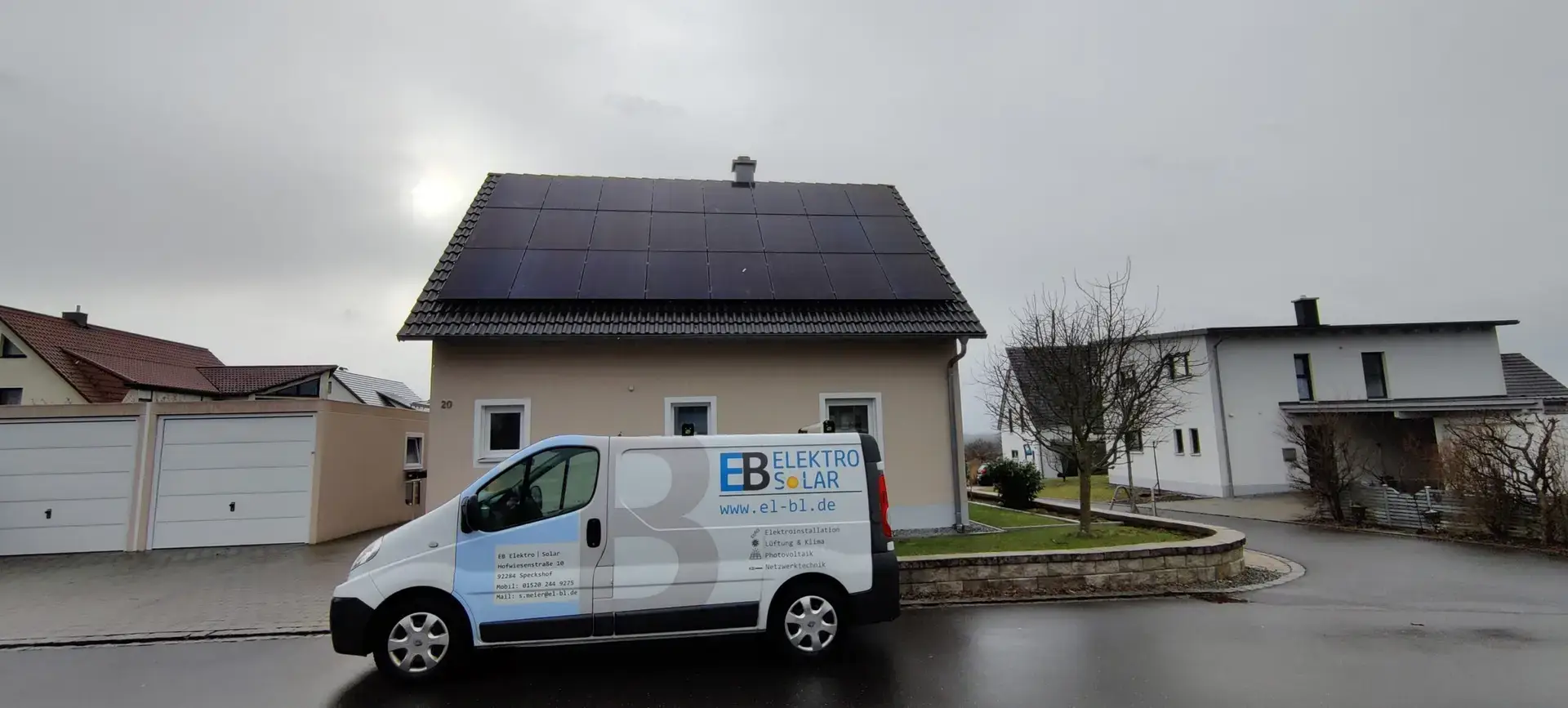 Transporter von EB Elektro Solar vor einem Haus mit Solarmodulen auf dem Dach in einer Wohngegend.