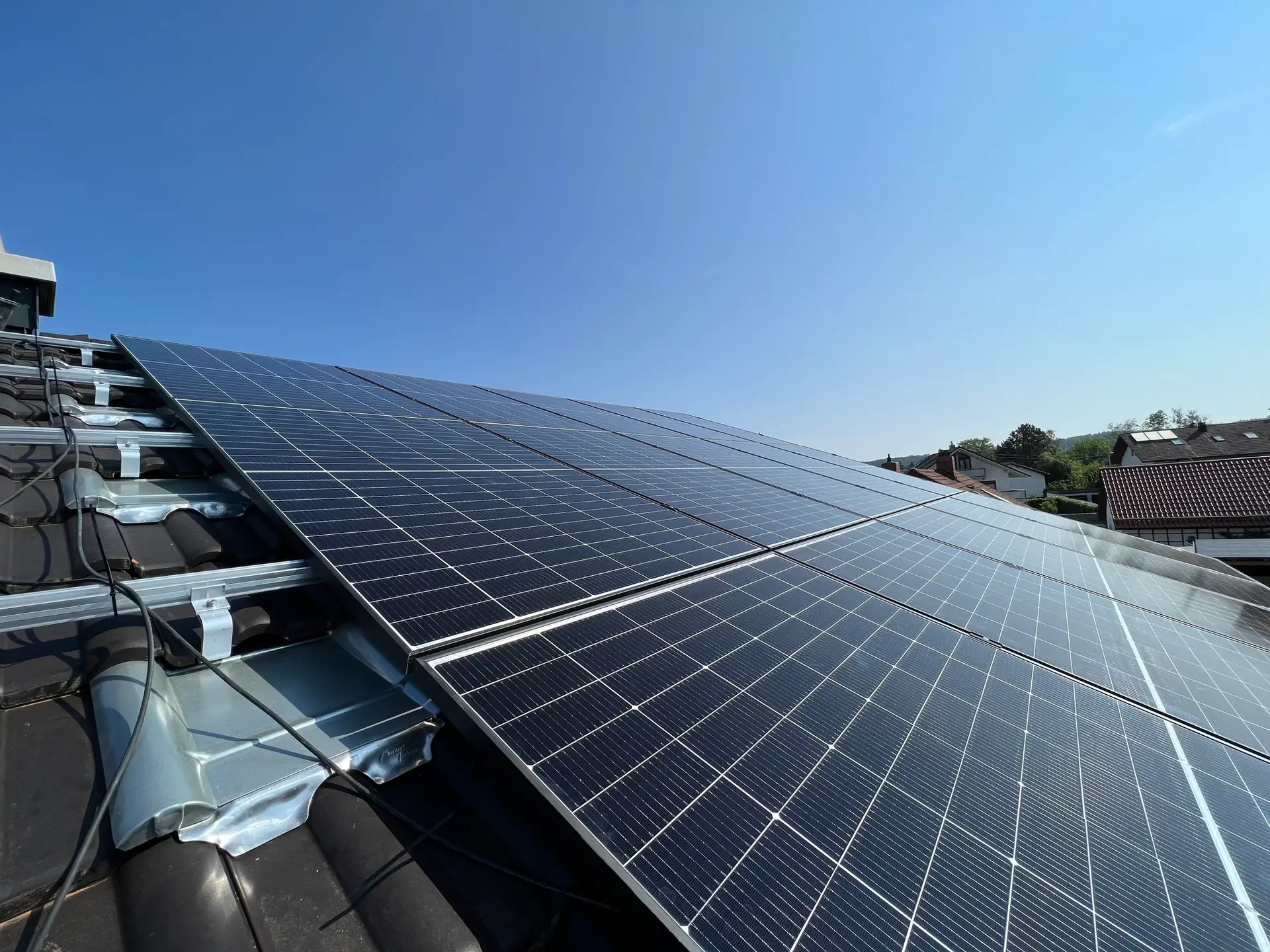 Solarmodule auf einem Hausdach an einem sonnigen Tag, symbolisieren erneuerbare Energie und Nachhaltigkeit.