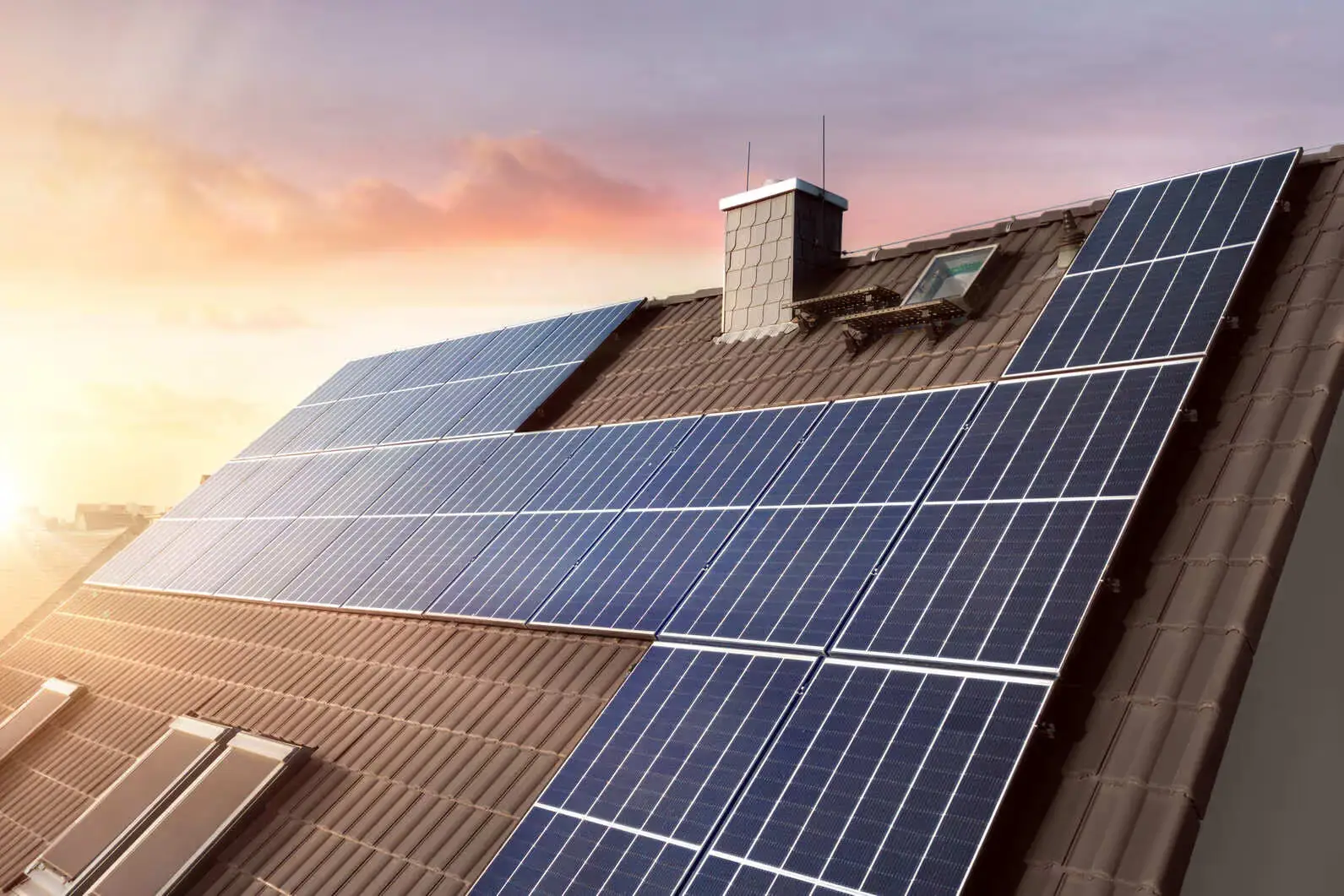 Solarmodule auf einem Hausdach bei Sonnenaufgang, nachhaltige Energiegewinnung durch Photovoltaik.