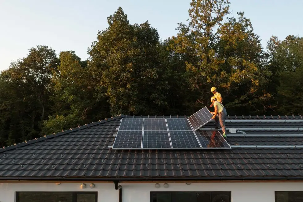 Montage von Solarpanels auf einem Hausdach von Arbeitern bei Sonnenuntergang, Nachhaltigkeit und erneuerbare Energie.