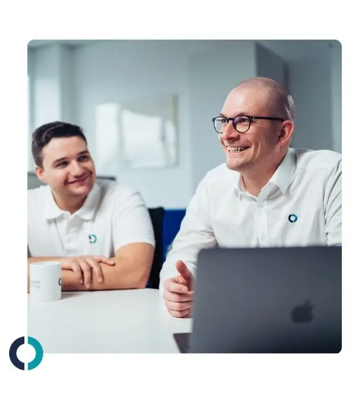 Mitarbeiter im Büro lächelnd in Gesprächssituation, professionelles Auftreten, Teamarbeit und Zusammenarbeit.