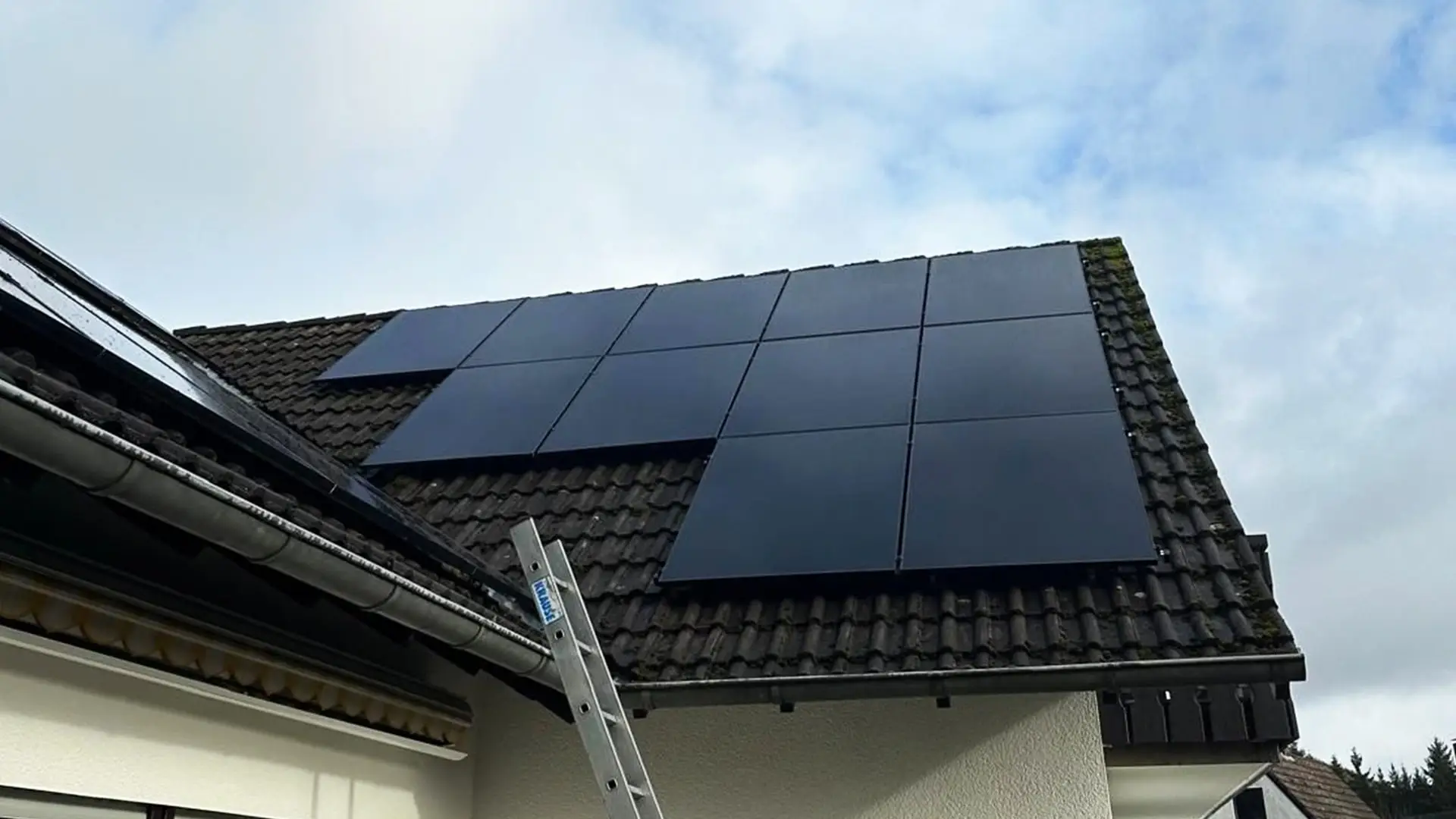 Solarmodule auf einem Hausdach unter bewölktem Himmel installiert. Nachhaltige Energieerzeugung.