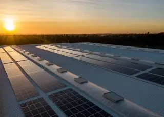 Sonnenaufgang über Solarmodulen auf einem Flachdach, nachhaltige Energieerzeugung und umweltfreundlicher Strom.