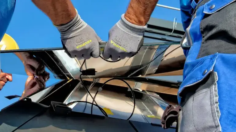 Zwei Arbeiter installieren Solarpanels auf einem Dach bei sonnigem Wetter, Nahaufnahme ihrer Hände und Werkzeuge.