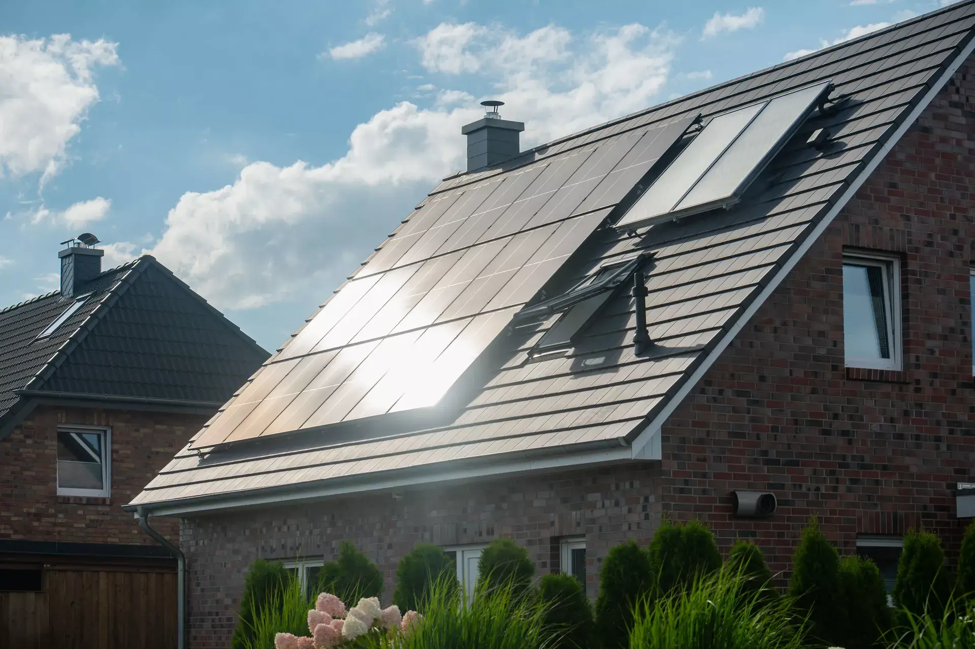 Ziegelhausdach mit Solaranlagen unter blauem Himmel, Effizienz der erneuerbaren Energie im Wohnbereich.