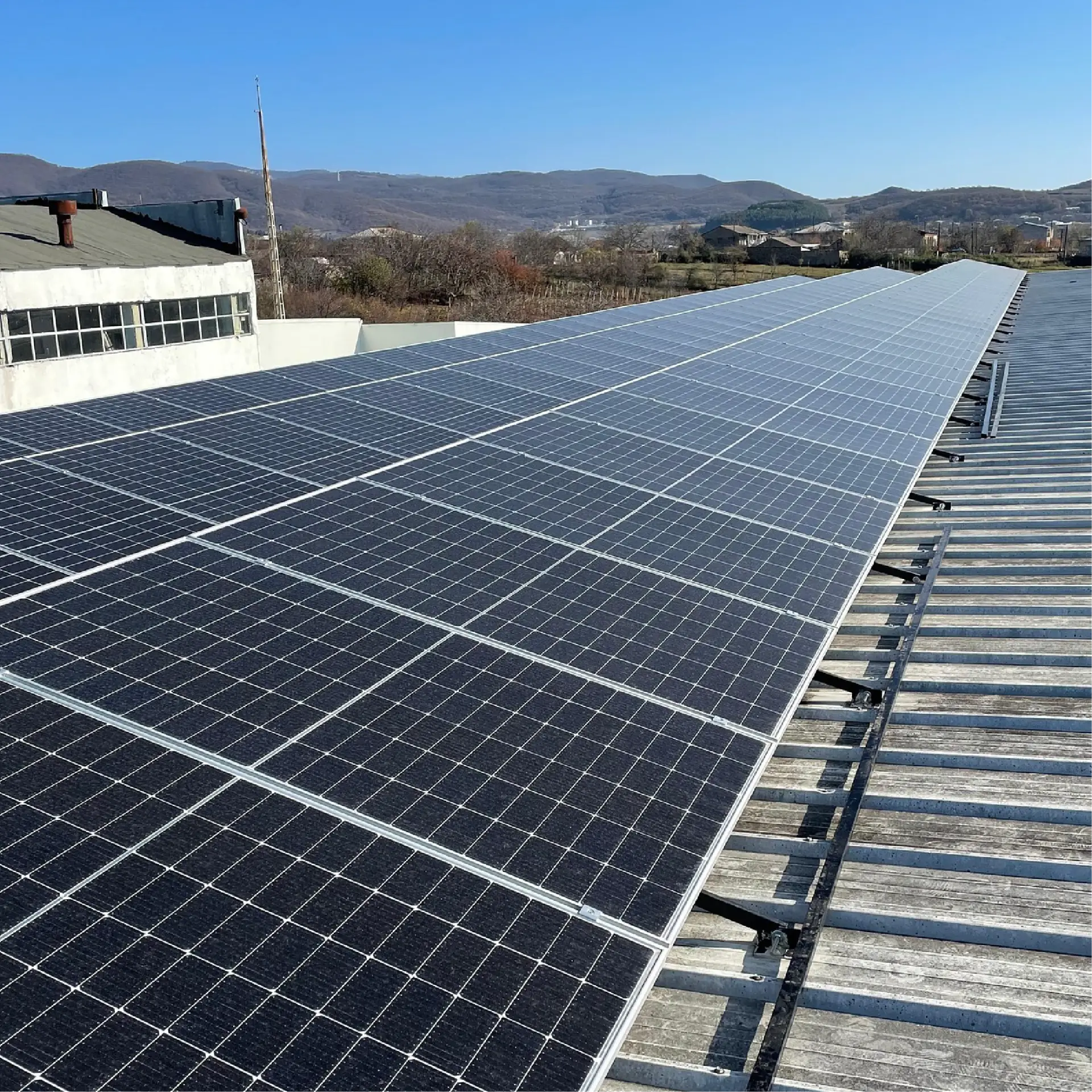 Solaranlage auf Dach mit Bergblick an sonnigem Tag. Nachhaltige Energiequelle in ländlicher Umgebung.
