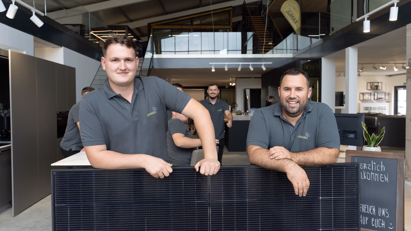 Zwei Männer in einem modernen Büro, die ein Solarpanel präsentieren.