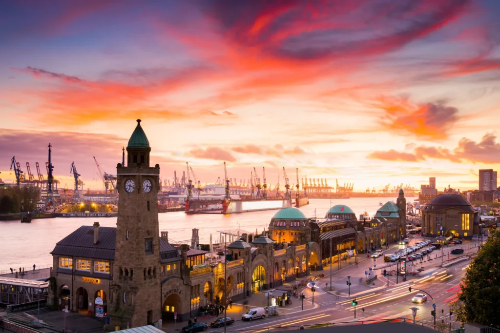 Sonnenuntergang am Hafen von Hamburg mit historischen Gebäuden und Kränen im Hintergrund. Romantische Hafenstimmung.