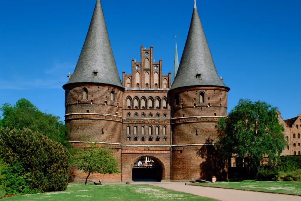 Holstentor Lübeck: Historisches Stadttor aus Backstein mit zwei Türmen, blauer Himmel im Hintergrund, Frühling.