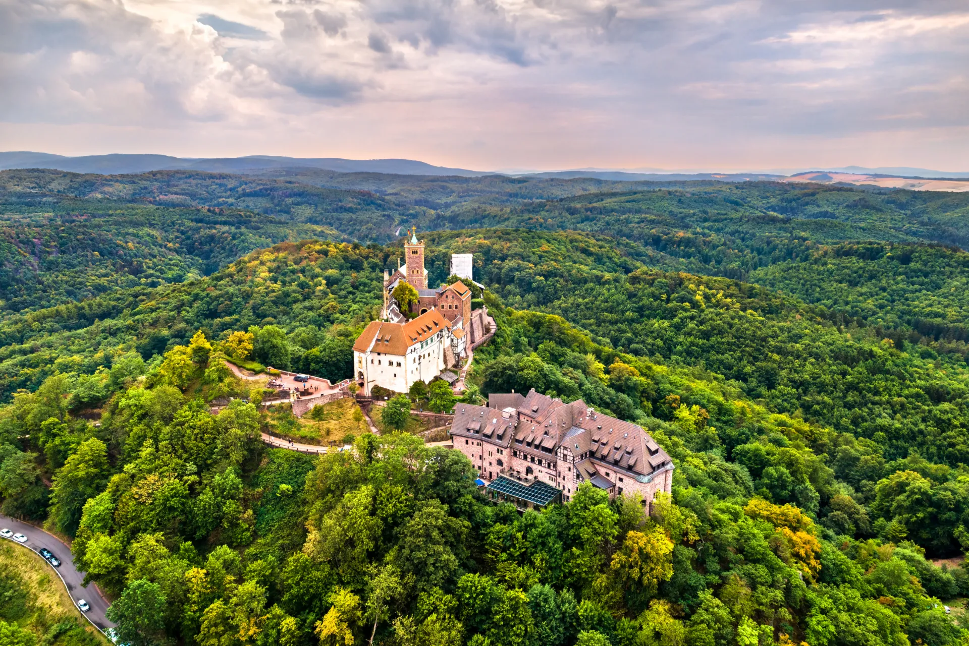 Luftaufnahme der Wartburg, umgeben von grünen Wäldern, unter bewölktem Himmel in Thüringen, Deutschland.