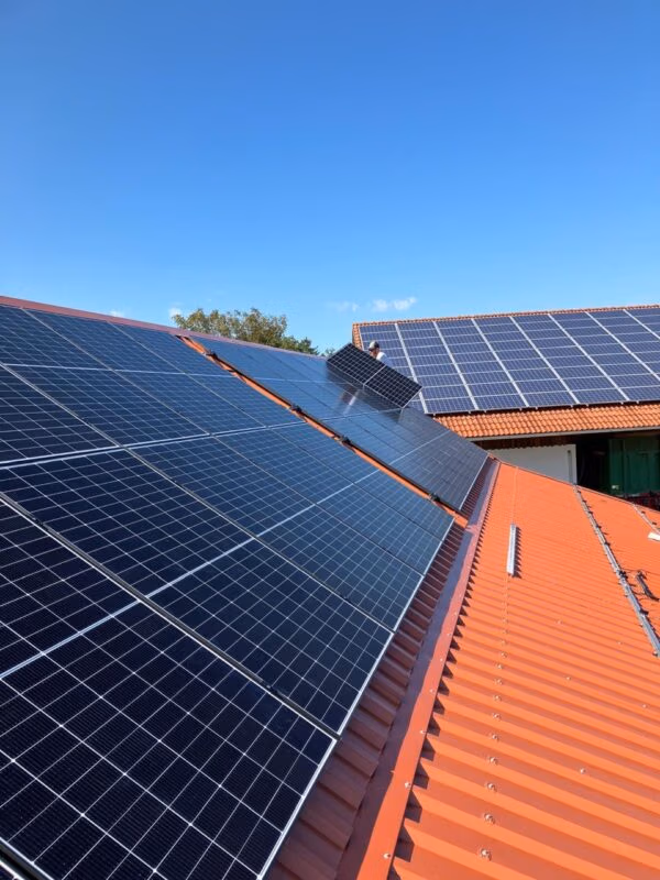 Solarmodule auf einem roten Dach unter klarem Himmel montiert, zur nachhaltigen Energiegewinnung.