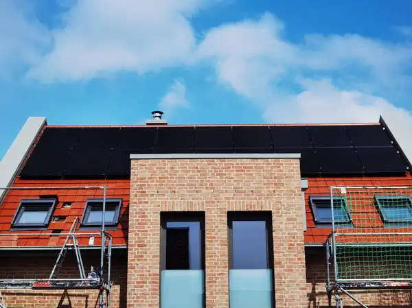 Flachdach mit installierten Solarmodulen vor blauem Himmel, moderne Architektur mit Backsteinfassade.